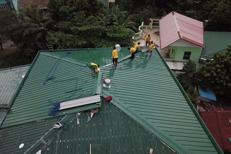 Équipe au travail sur une couverture en tôle verte, vue du ciel