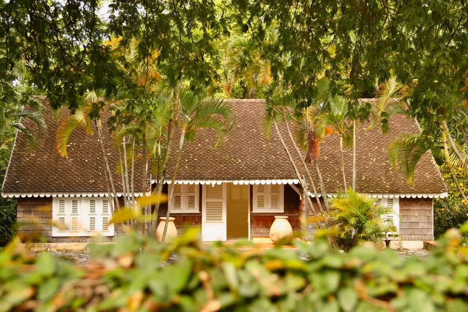 Maison en bois aux persiennes blanches sous les arbres