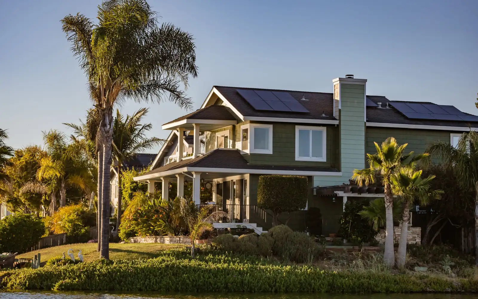 Maison entourée de palmiers, panneaux solaires sur le toit