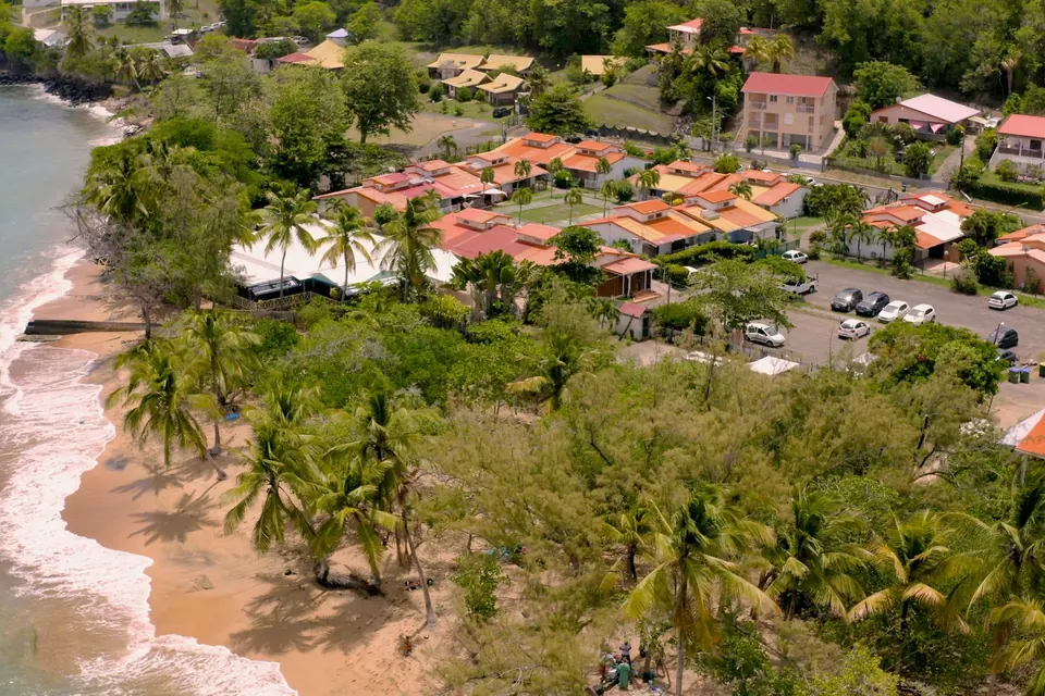 Résidence en bord de plage entourée de cocotiers, vue du ciel