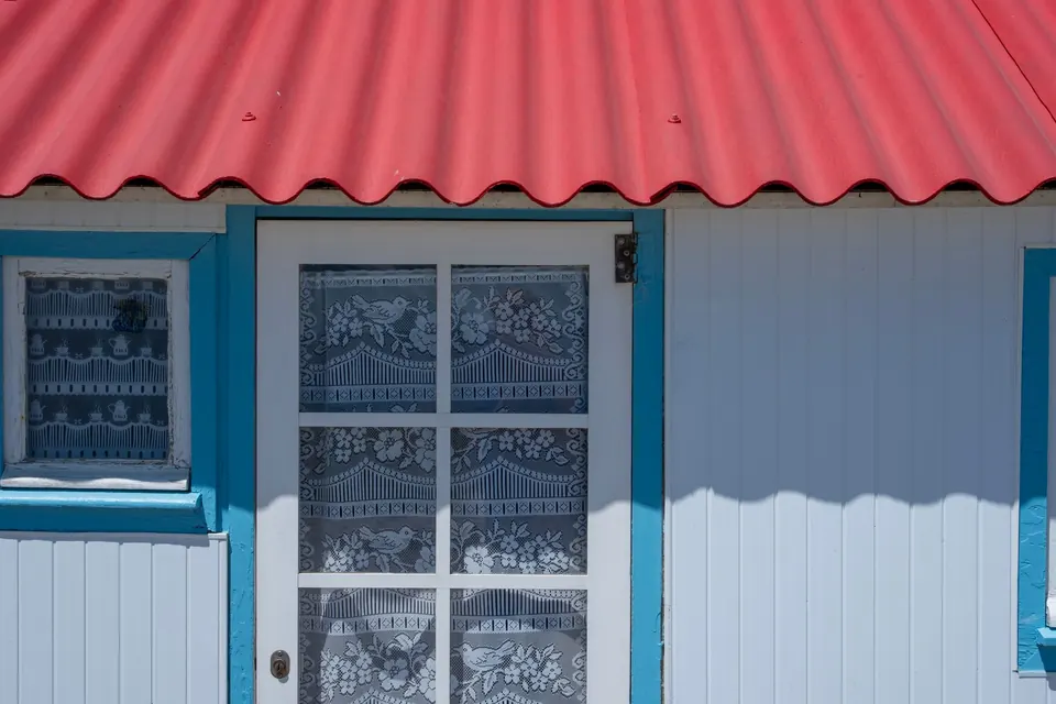 Tôle ondulée rouge au-dessus de la façade en bois d'une petite maison